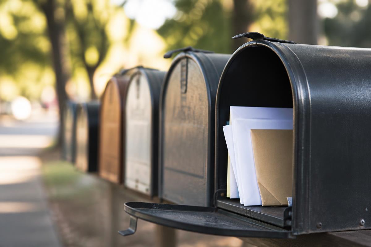 Row of neighborhood mailboxes with envelopes inside